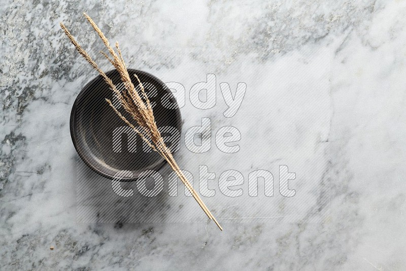 Wheat stalks on Black Pottery Oven Plate on grey marble flooring, Top view