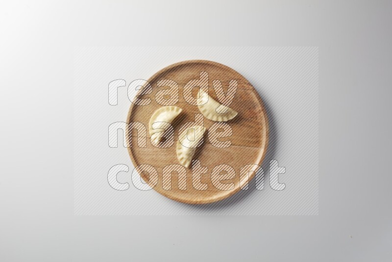 Three Sambosas on a wooden round plate on a white background