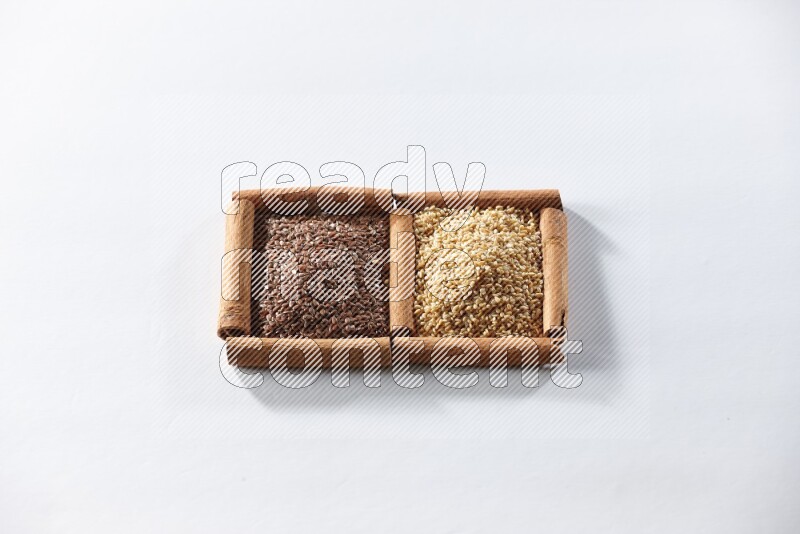 مربعان من أعواد القرفة ممتلئان ببذور الكتان وبذور السمسم علي خلفية بيضاء