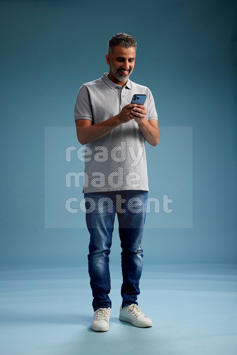 Man Standing texting on phone on blue background