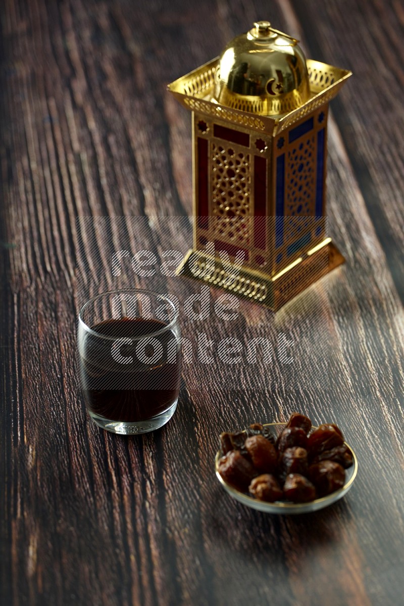 A golden lantern with different drinks, dates, nuts, prayer beads and quran on brown wooden background