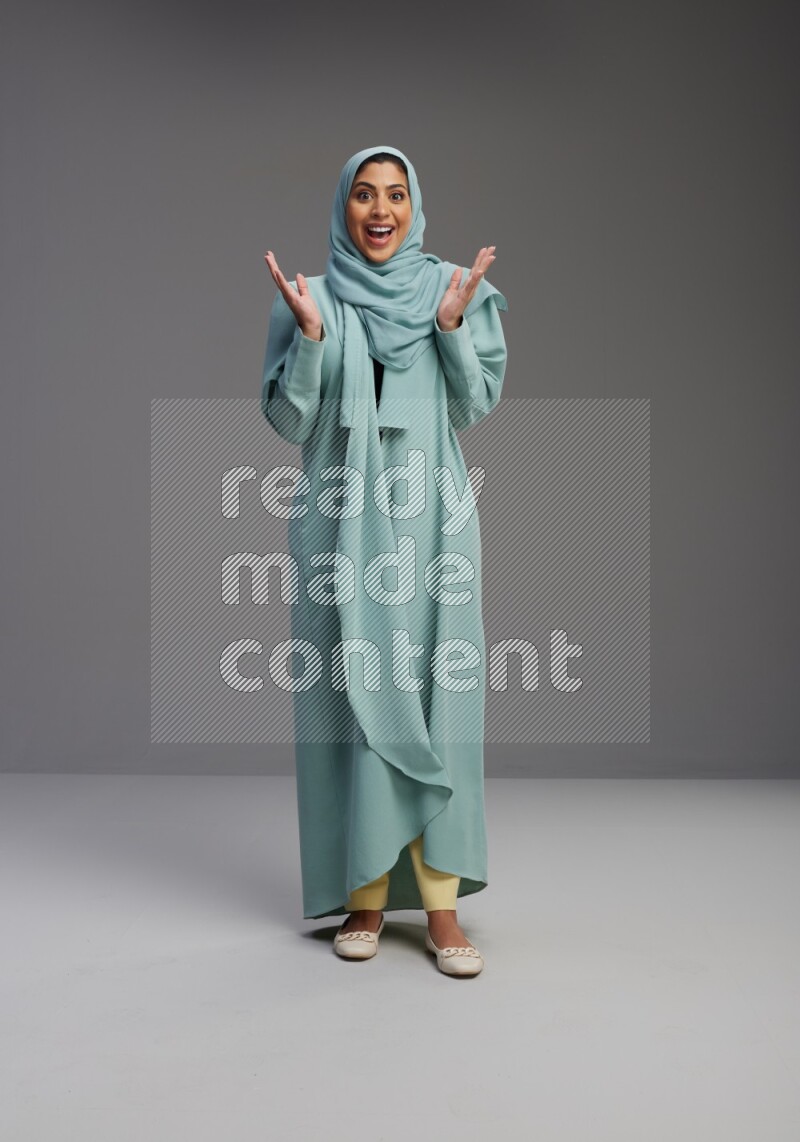 Saudi Woman wearing Abaya standing interacting with the camera on Gray background