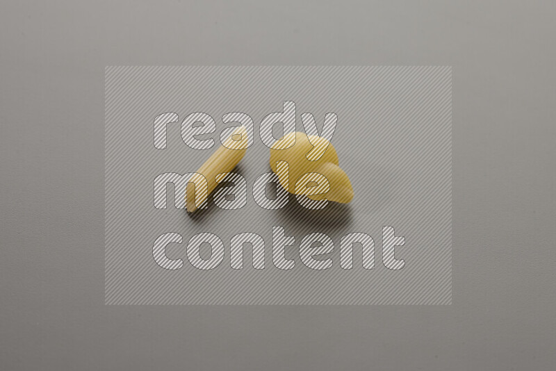 Mini penne pasta with other types of pasta on grey background