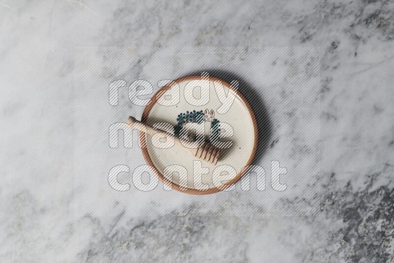 Decorative pottery plate with wooden honey dipper in it on grey marble background