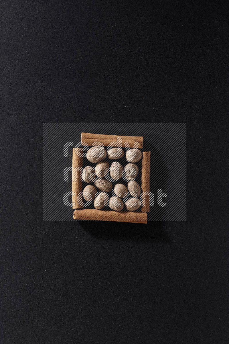 A single square of cinnamon sticks full of nutmeg on black flooring