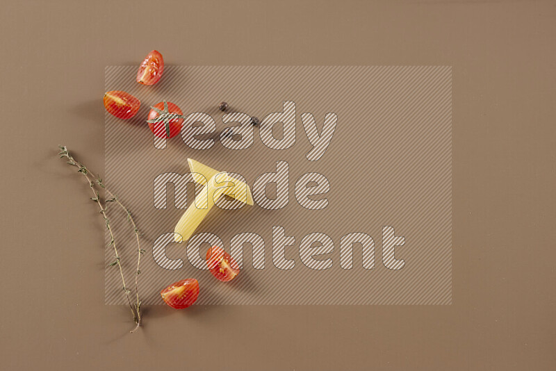 Raw pasta with different ingredients such as cherry tomatoes, garlic, onions, red chilis, black pepper, white pepper, bay laurel leaves, rosemary and cardamom on beige background