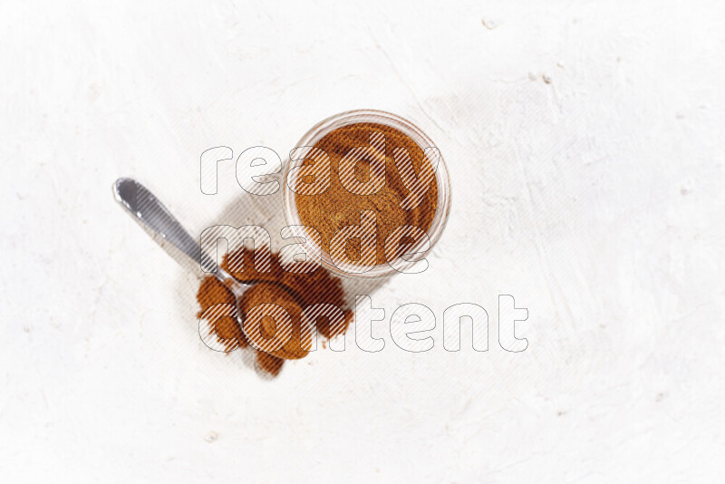 A glass jar full of ground paprika powder on white background