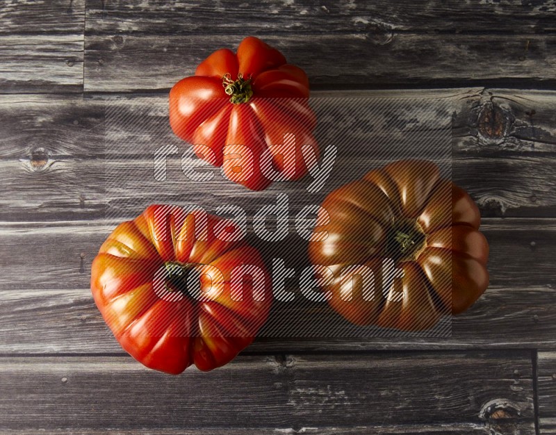 three heirloom tomatoes topview on a textured vinyl background
