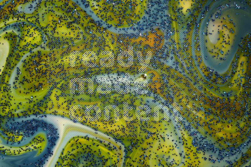 A close-up of sparkling blue glitter scattered on swirling blue and yellow background
