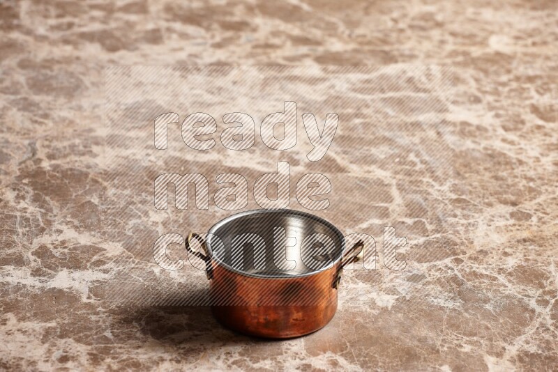 A small copper pot on beige marble background