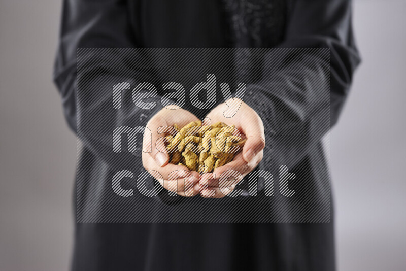 Woman in abaya holding different kinds of spices in different positions