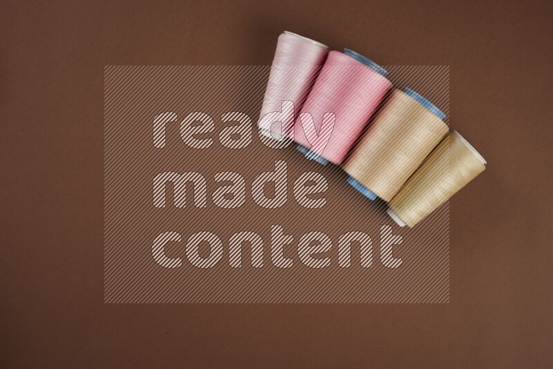 مجموعة من أدوات الخياطة والتفصيل زهرية اللون على خلفية بنية