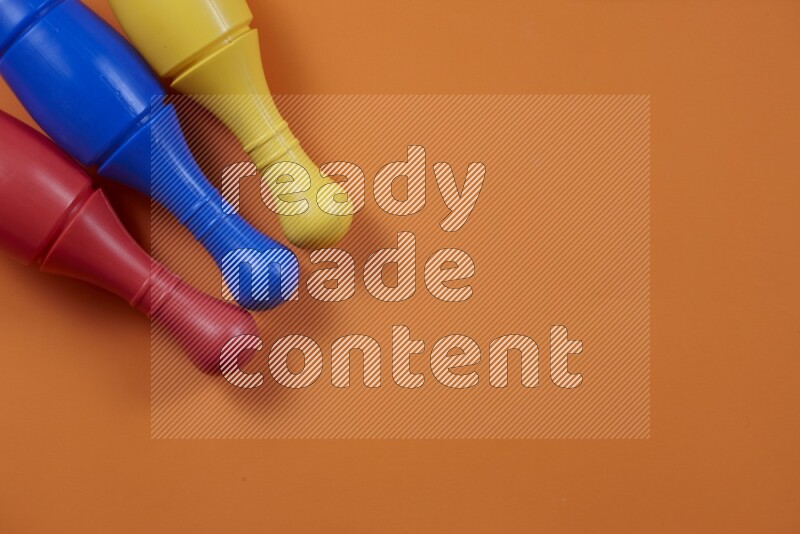 Multicolored plastic bowling pins on different colored backgrounds background (kids toys)