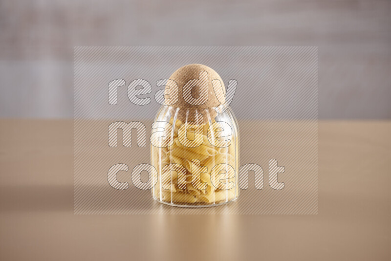 Raw pasta in glass jars on beige background