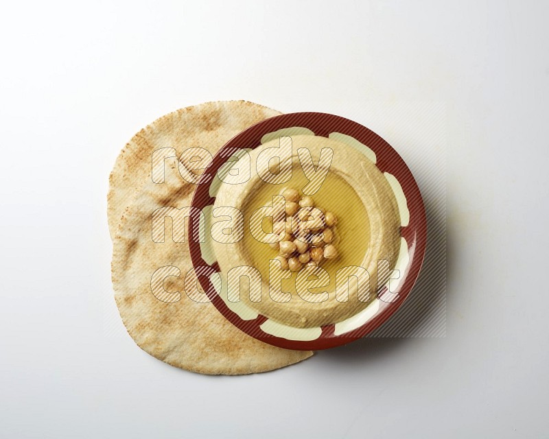 Hummus in a traditional plate garnished with roasted chickpeas  on a white background