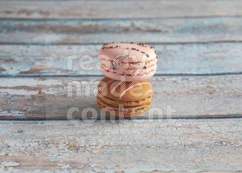 45º Shot of of two assorted Brown Irish Cream, and pink orange blossom  macarons on light blue background