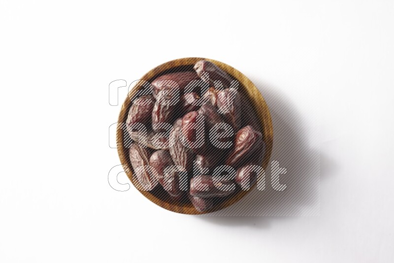 Dates in a wooden bowl on white background