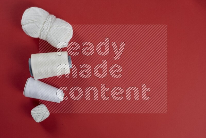 مجموعة من أدوات الخياطة والتفصيل بيضاء اللون على خلفية حمراء