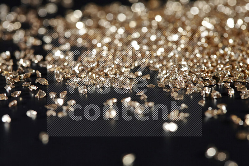 Gold shimmering fragments of glass scattered on a black background