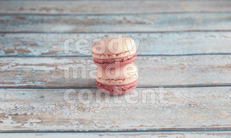 45º Shot of two Pink Litchi Raspberry macarons on light blue wooden background