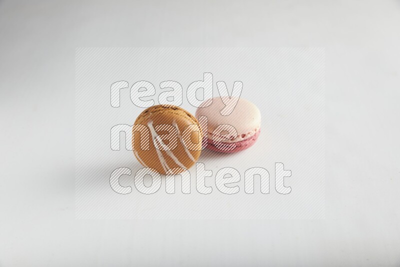 45º Shot of of two assorted Brown Irish Cream, and Pink Litchi Raspberry macarons on white background