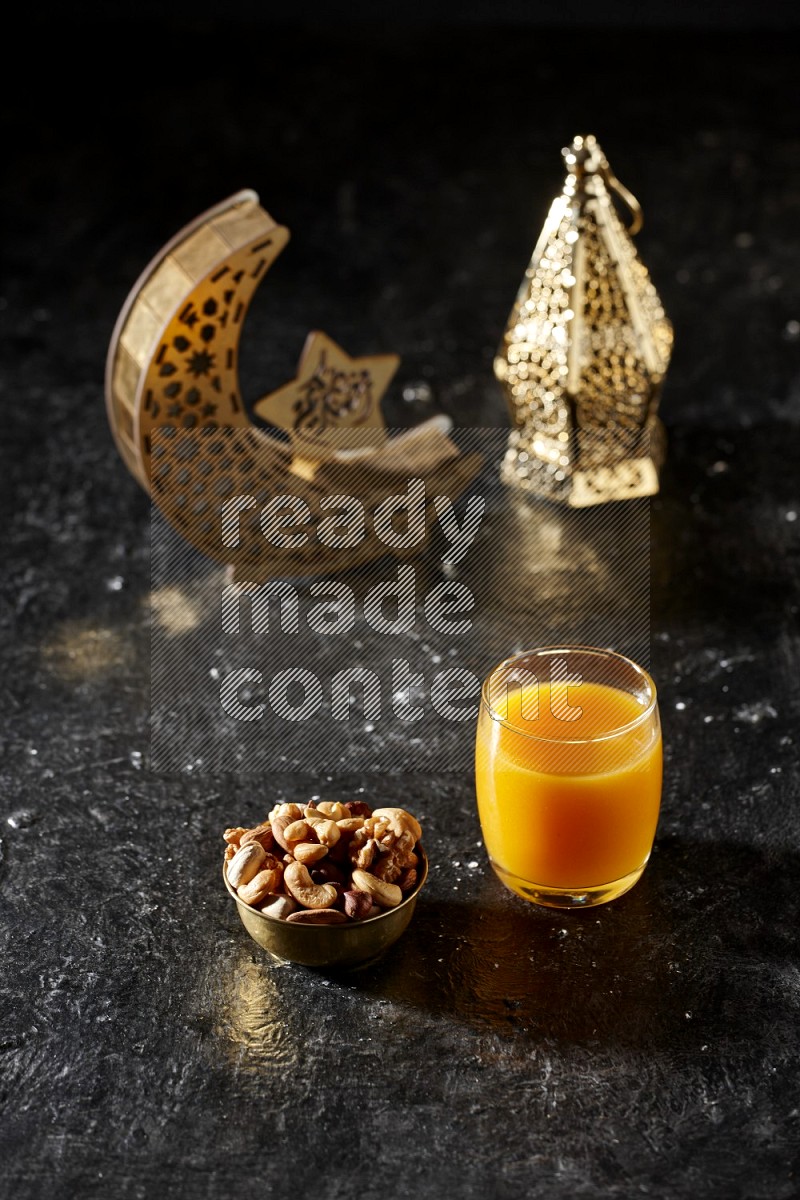 Nuts in a metal bowl with qamar el din beside golden lanterns in a dark setup