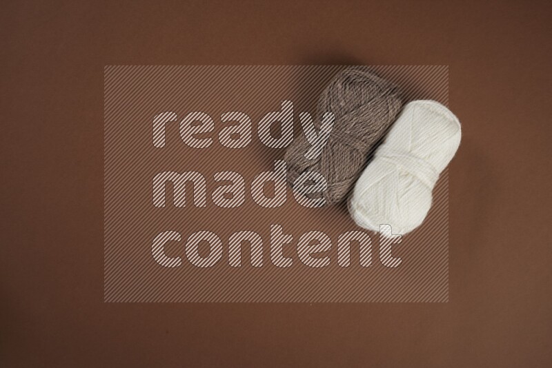 مجموعة من أدوات الخياطة والتفصيل بيضاء وبنية اللون على خلفية بنية