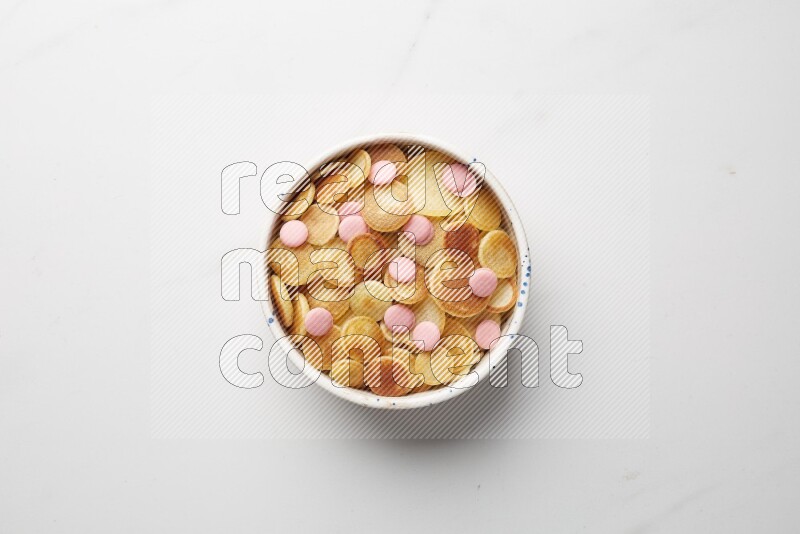 Top-view shot of pink chocolate chips cereal pancakes in a round bowl on white background