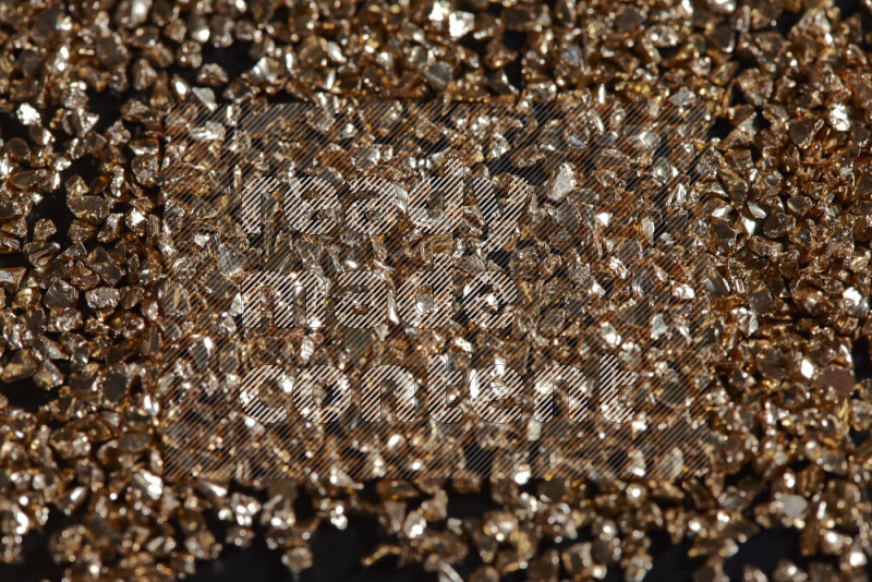 Gold shimmering fragments of glass scattered on a black background