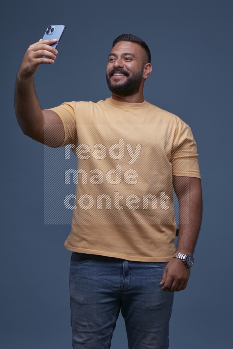 A man Taking A Selfie on Blue Background wearing Orange T-shirt