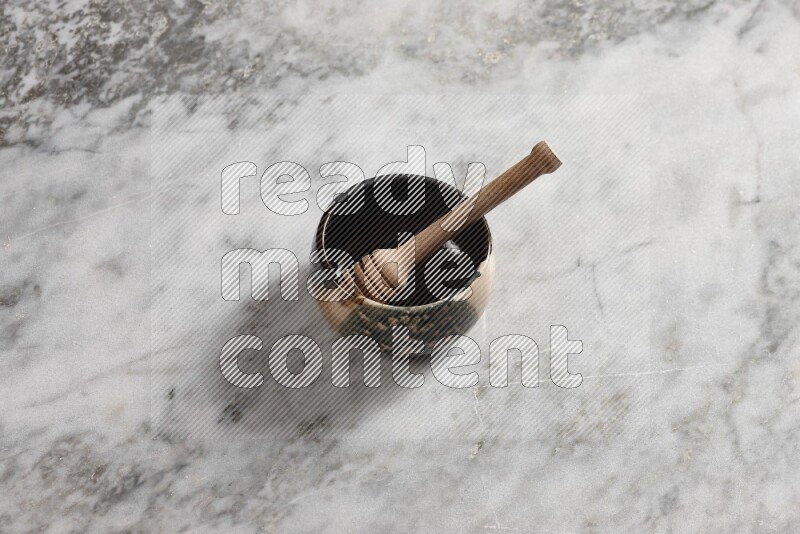 Multicolored pottery bowl with wooden honey dipper in it on grey marble background