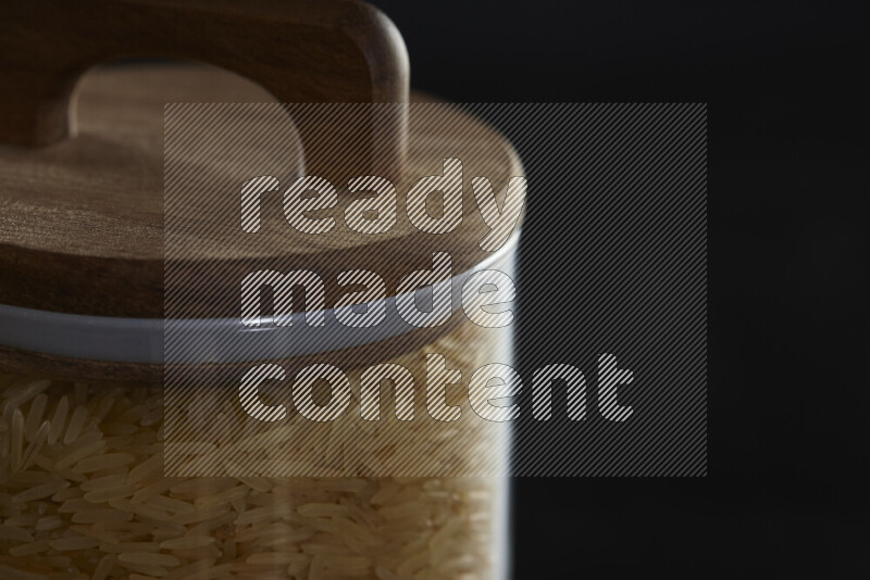 Basmati golden rice in a glass jar on black background