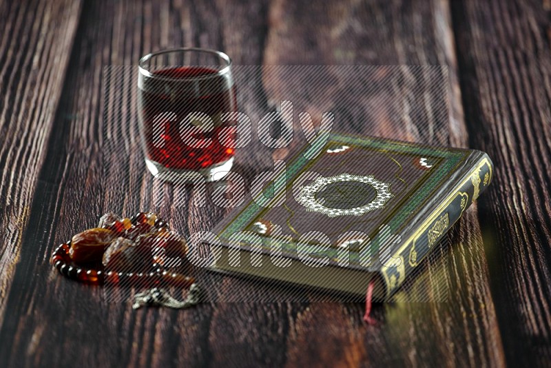 Quran with dates, prayer beads and different drinks on wooden background