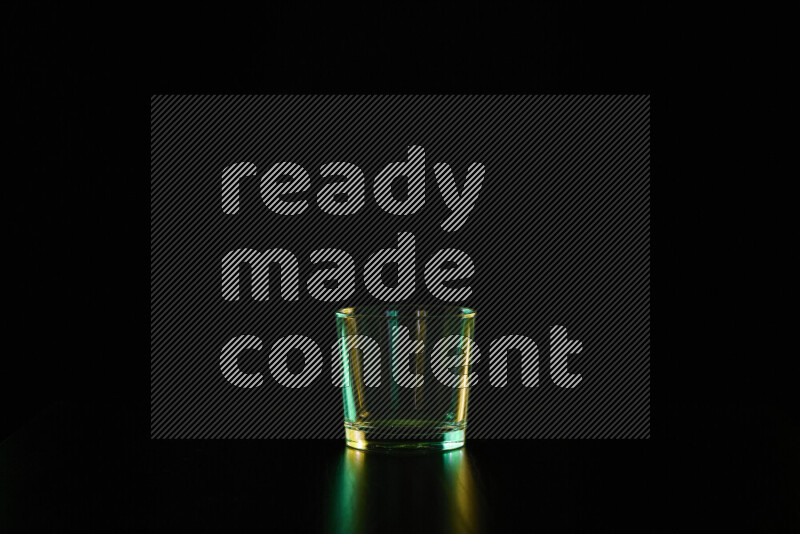 Glassware with rim light in green and yellow against black background