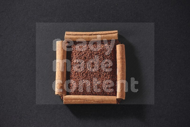 A single square of cinnamon sticks full of garden cress on black flooring