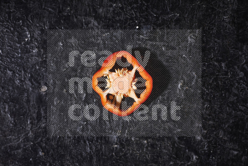 Red bell pepper slices on black background