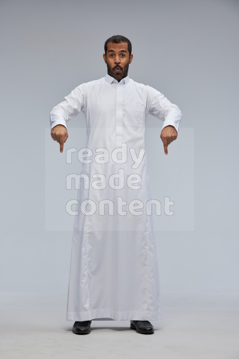 Saudi man Wearing Thob standing interacting with the camera on Gray background