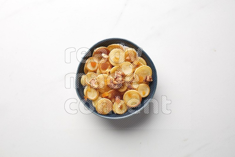 Top-view shot of walnut and apricot cereal pancakes in a round bowl on white background