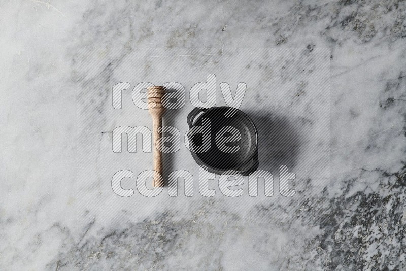 Black Pottery Bowl with wooden honey handle on the side on grey marble flooring, Top view