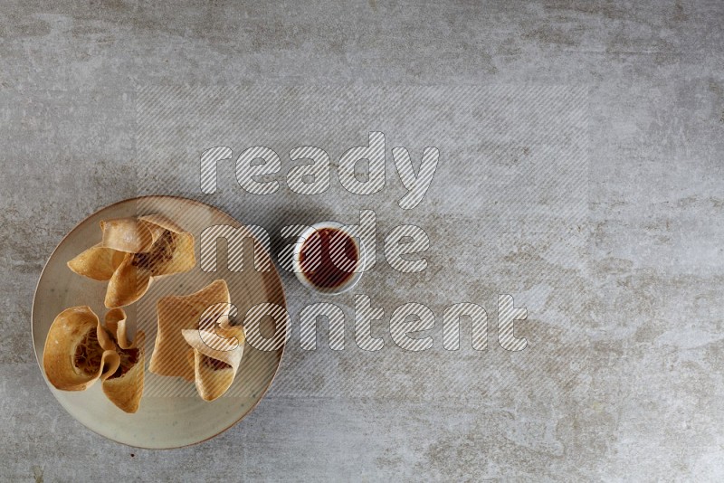 wonton cups with soy sauce ramkin on multi colored pottery on grey textured counter top