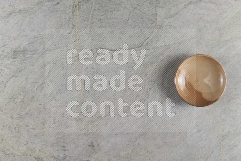 طبق من الفخار باللون البيج على خلفية من الرخام الرمادي