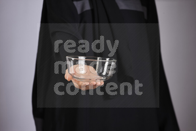 A woman in black abaya holding different glassware in different positions