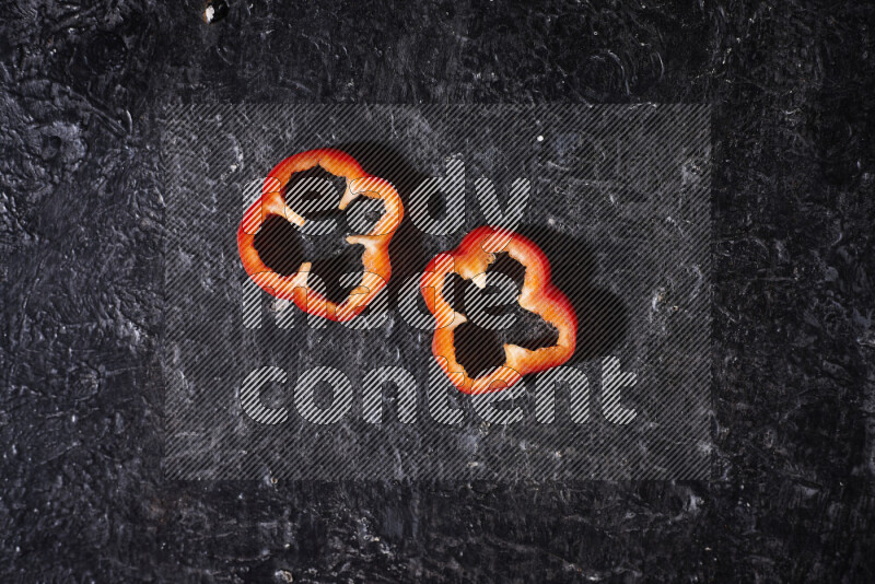 Red bell pepper slices on black background