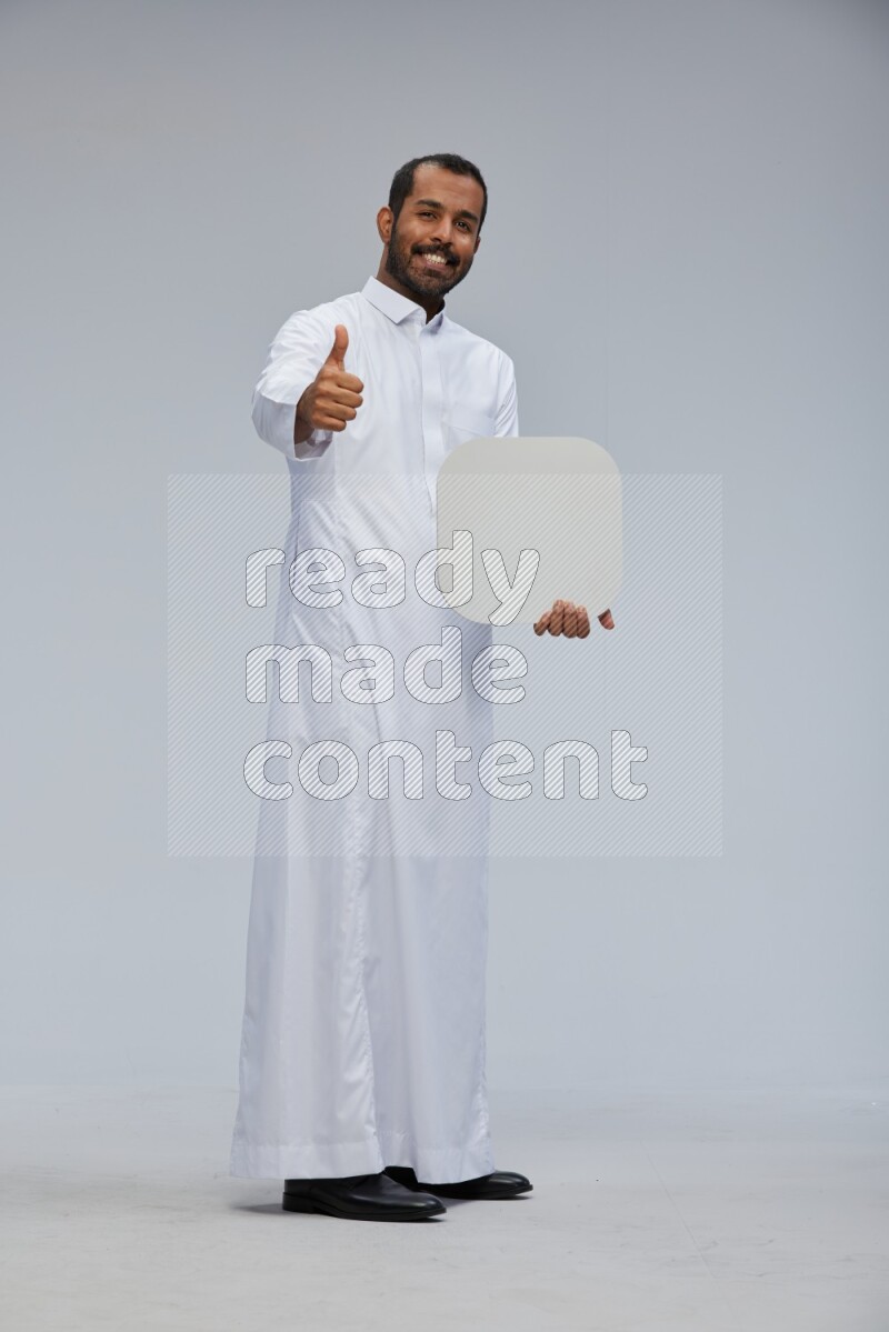 Saudi man wearing Thob standing holding social media sign on Gray background