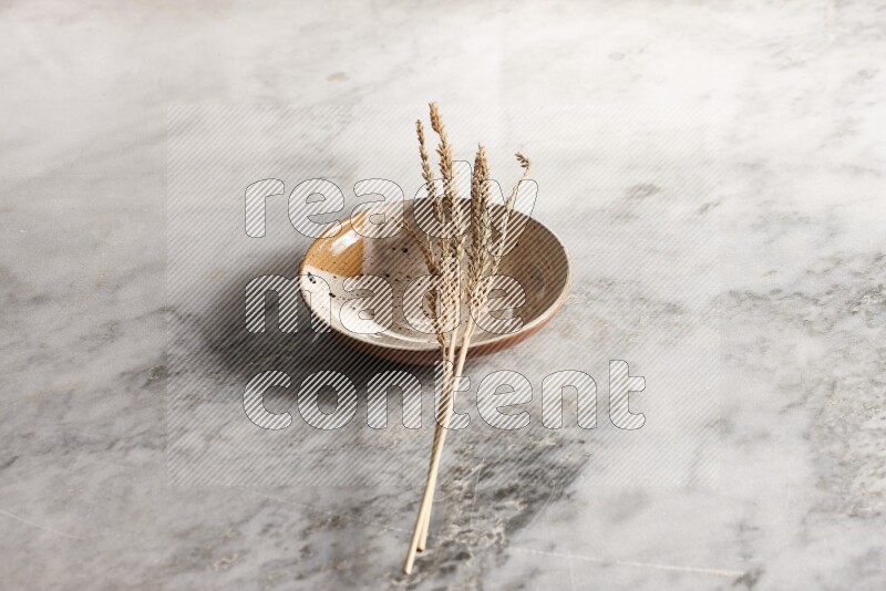 Wheat stalks on multicolored pottery plate on grey marble background