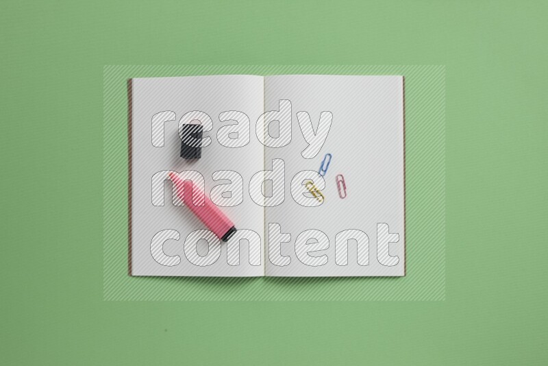 دفتر ملاحظات مفتوح فارغ مع مستلزمات مدرسية مختلفة على خلفية خضراء