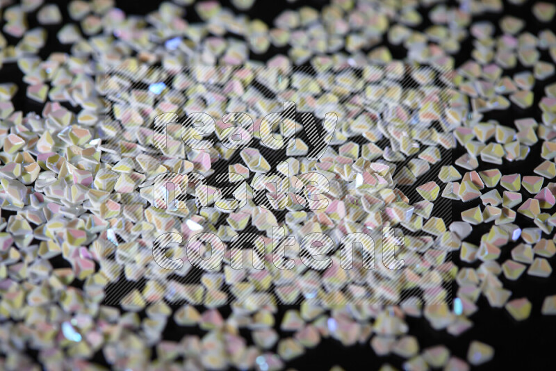 قطع صغيرة بلاستيكية ملونة للزينة متناثرة على خلفية سوداء