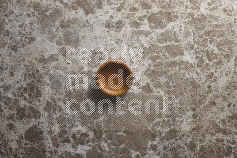 A wooden bowl on beige marble background