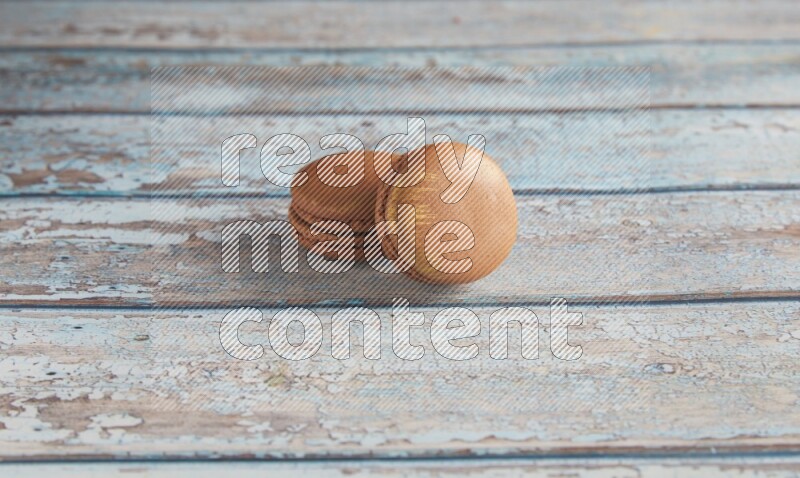 45º Shot of two Brown Coffee macarons on light blue wooden background