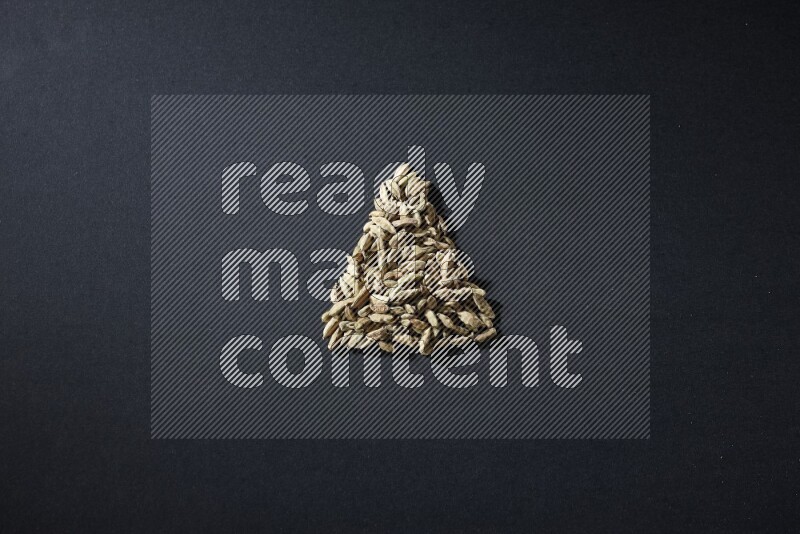 Cardamom in a triangle shape on black flooring